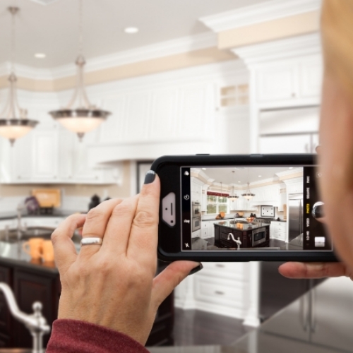 Woman using phone to take picture of kitchen.