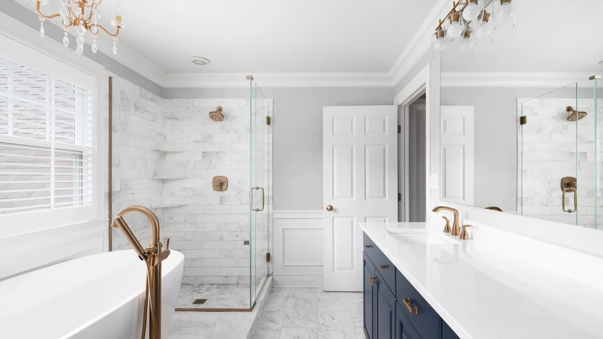 Modern white bathroom remodel with walk-in shower, blue cabinets, white quartz countertop and white tub.